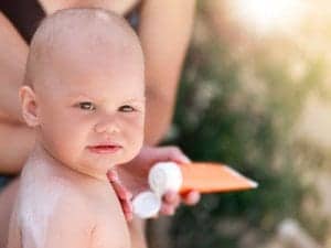parent applying sunscreen to baby