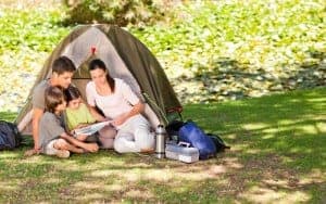 A family reading together outside of their tent.