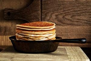 pancake stack in a cast iron skillet against wooden surface