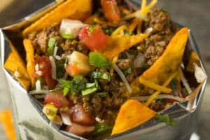 walking taco with chips, meat, onion, tomatoes, and more